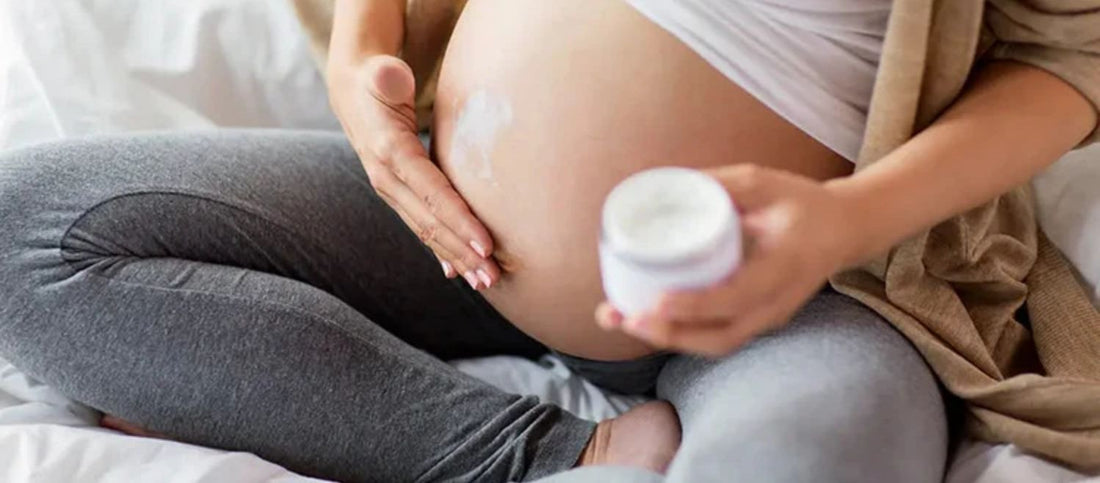 A woman rubs special cream on her to her pregnant bump