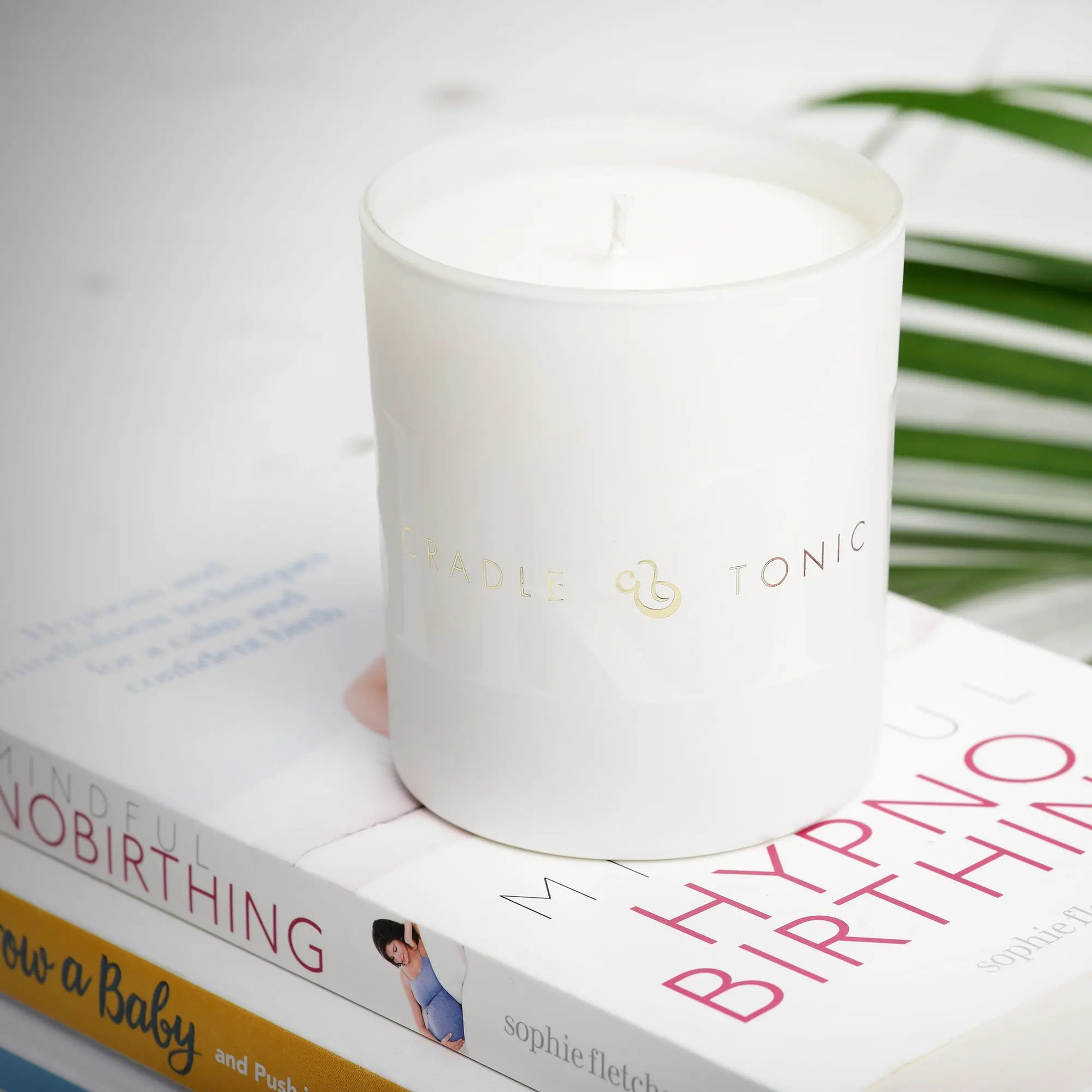 Cradle & Tonic Birthing Candle placed on hypnobirthing books, perfect for creating a serene atmosphere during childbirth and prenatal relaxation.
