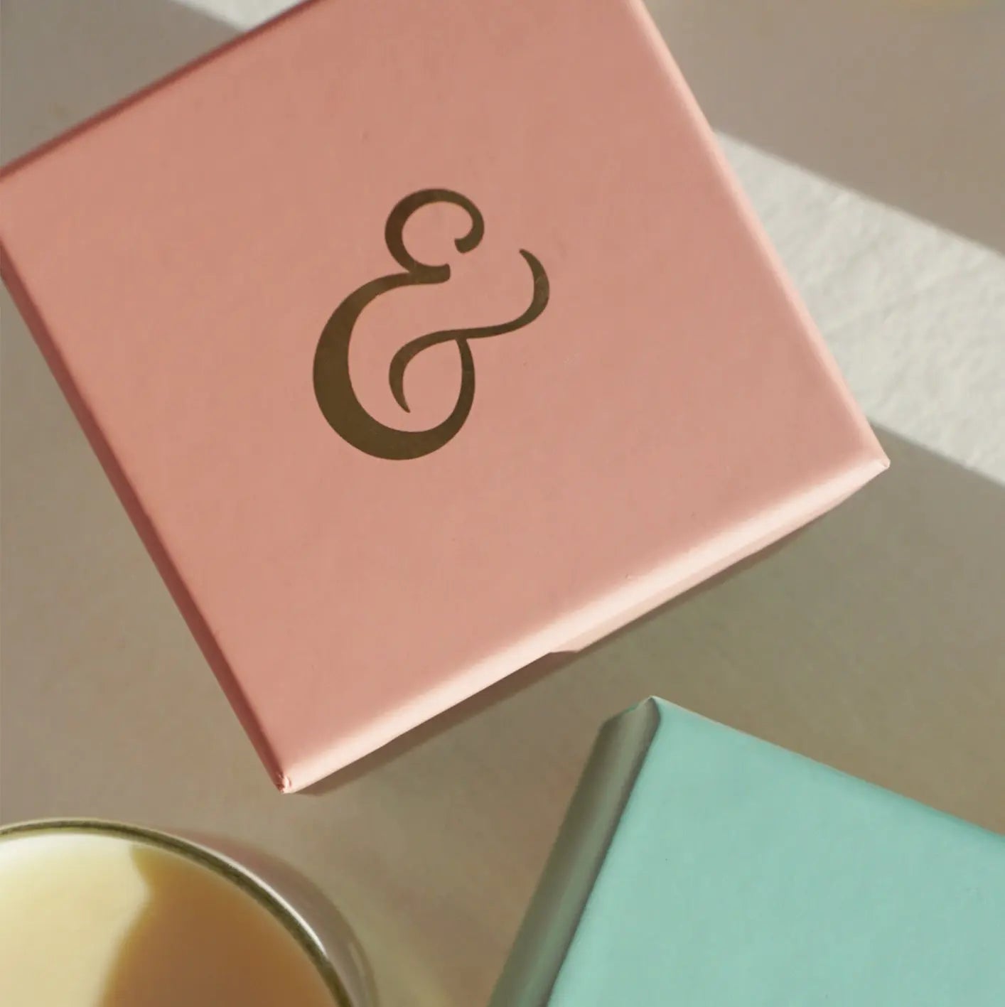 Top view of Cradle & Tonic candle packaging in pink with gold ampersand, highlighting elegant branding for pregnancy-safe aromatherapy candles.