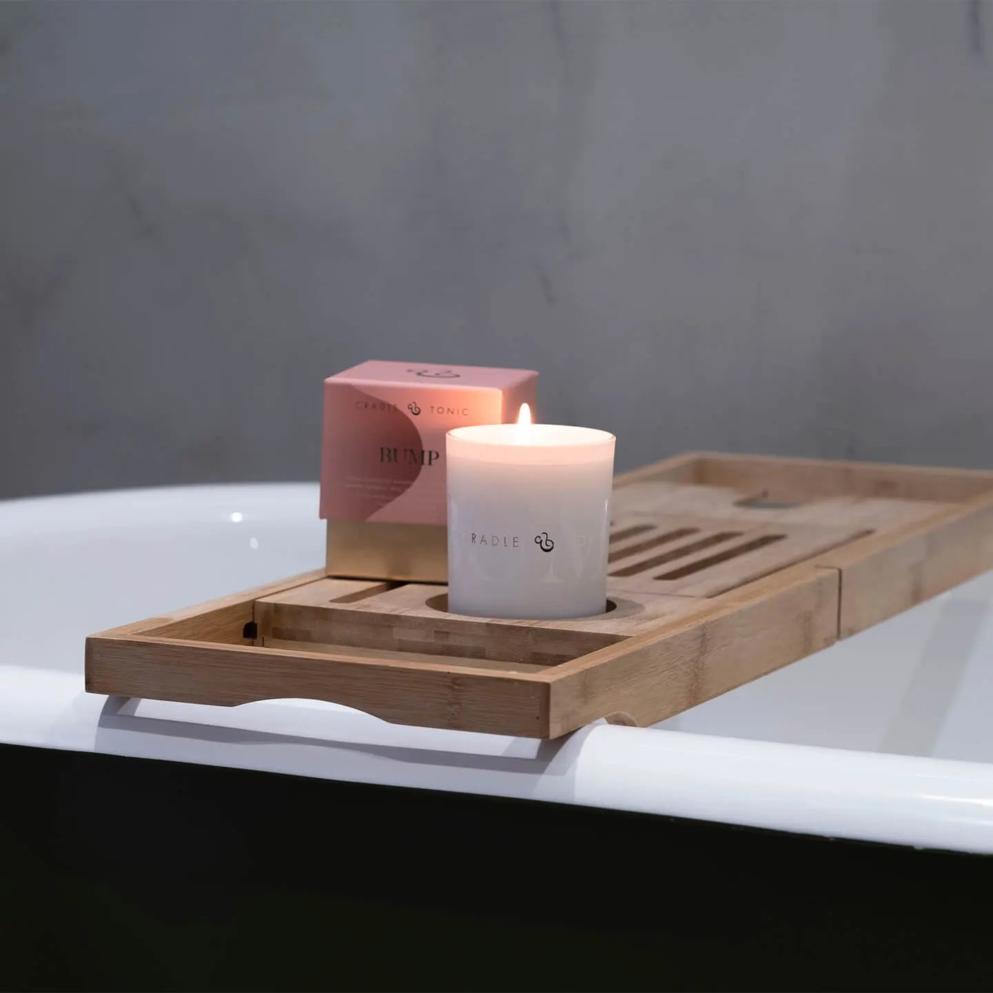 Pregnancy Candle by Cradle & Tonic lit on a bamboo bath tray, creating a calming atmosphere for relaxation and self-care during pregnancy.